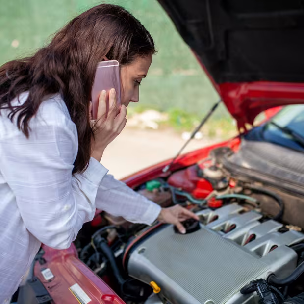 Customer on the phone about a car issue while checking under the bonnet before calling Central East Mechanical