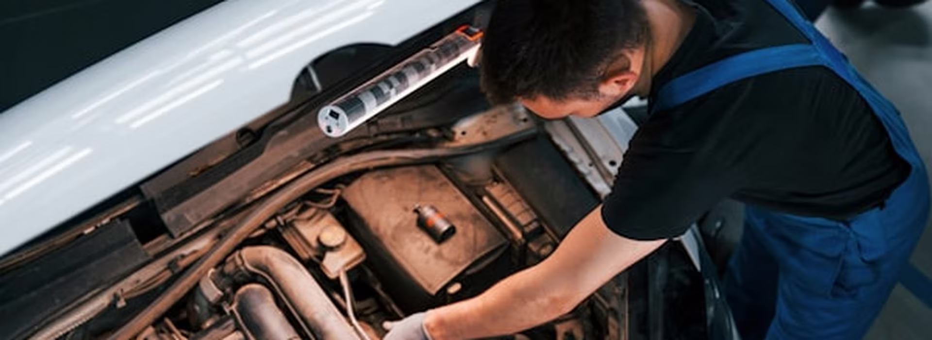 Mechanic working on an engine bay with the bonnet raised inside the Central East Mechanical workshop in Dapto