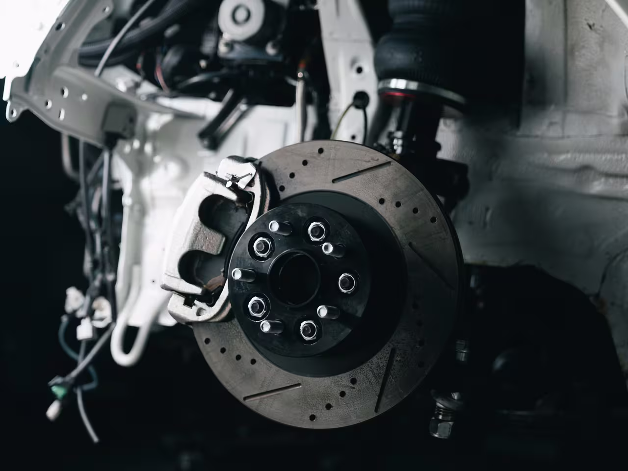 Close-up of a drilled and slotted brake disc and caliper removed from a vehicle at Central East Mechanical in Dapto
