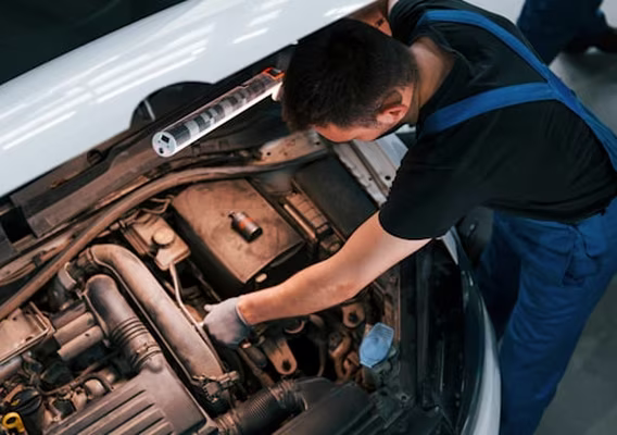Mechanic working on an engine bay with the bonnet raised inside the Dapto workshop